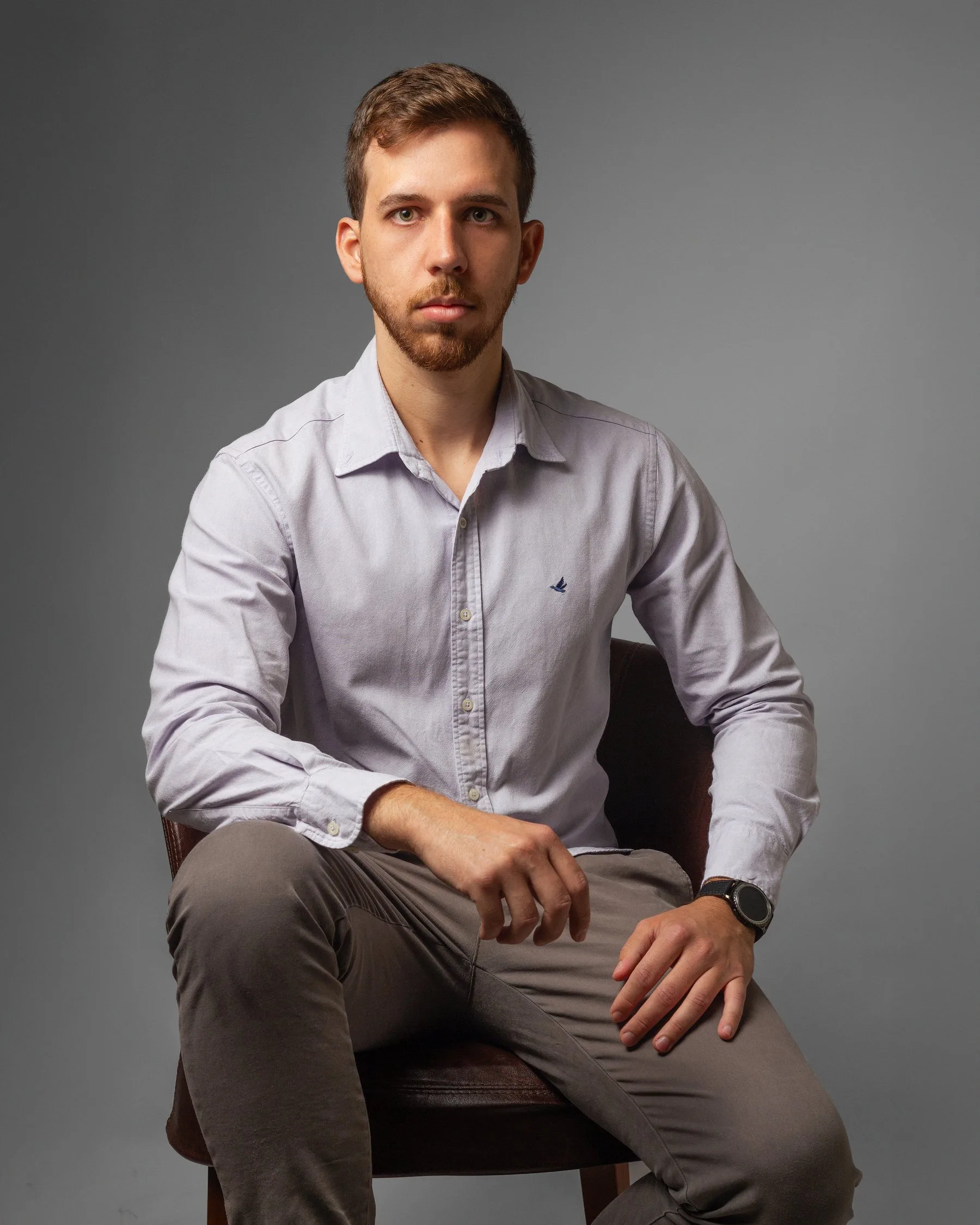 Dr. João Lucas Rosa sentado em poltrona de couro, camisa clara