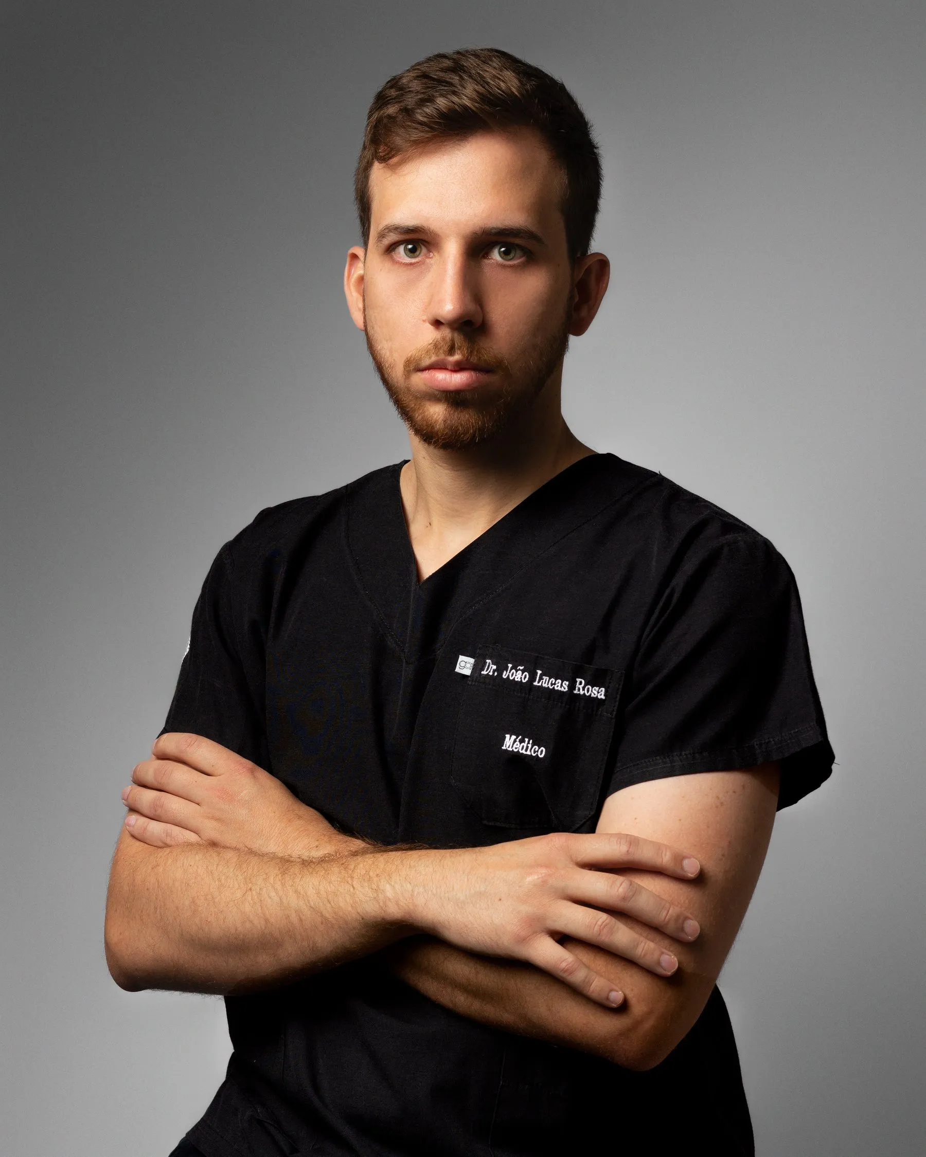 Dr. João Lucas Rosa de scrubs, braços cruzados